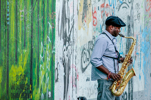 Berlin, Germany - May 14, 2014: street artist plays a sax in front of the Berlin Wall, East Side Gallery, Berlin, Germany