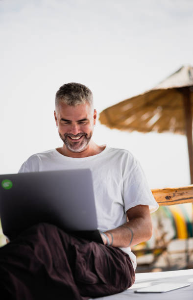 istock Man with his laptop working on the beach 1176019450