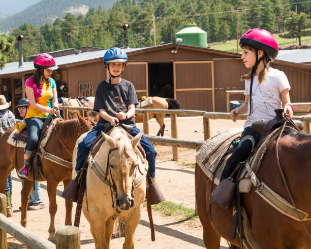 Family taking horseback riding lessons Middle aged woman and her son and daughter taking a horseback riding lesson in Colorado all horse riding stock pictures, royalty-free photos & images