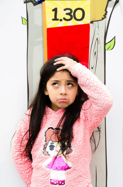 la niña está midiendo el crecimiento en el fondo de la pared. - bajo estatura humana fotografías e imágenes de stock