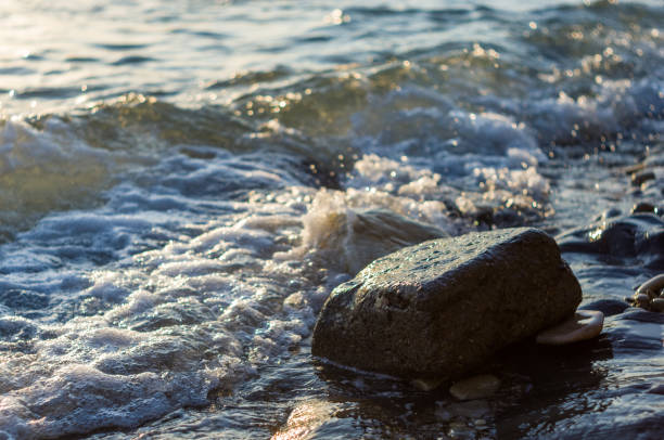 istock rocky sea shore with pebble beach, waves with foam 1176024887