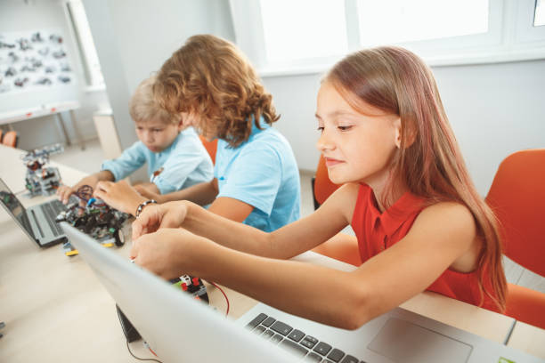 istock Robotics. Children having class making robots girl with wires smiling joyful close-up 1176032487