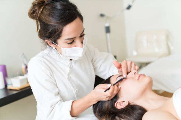 istock Cosmetician Brushing Hispanic Customer's Eyelash 1176032769