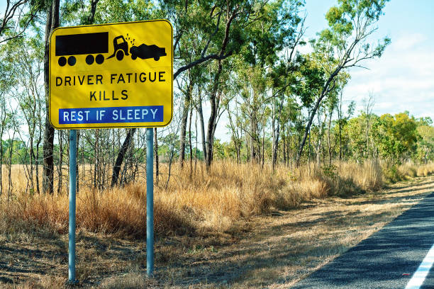 Highway Road Sign A yellow and black driver fatigue causes crashes alert sign on highway speed limit sign australia stock pictures, royalty-free photos & images