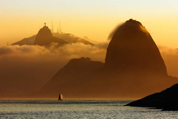 Sailing boat entering Guanabara Bay with Sugar Loaf Mountain and Christ the Redeemer Statue in background Sailing boat entering Guanabara Bay with Sugar Loaf Mountain and Christ the Redeemer Statue in background corcovado stock pictures, royalty-free photos & images