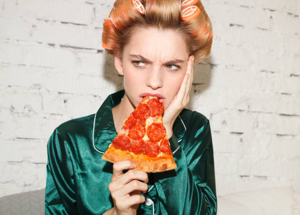 istock young ashamed female eating pizza in bed 1176041916