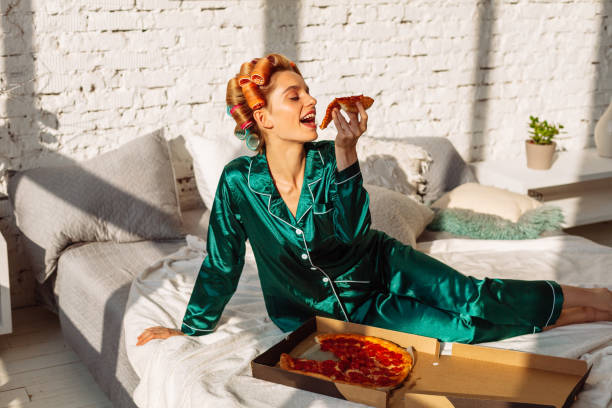 istock young happy female eating pizza in bed 1176041921