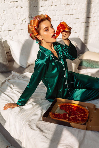 istock young sexy female eating pizza in bed 1176041925