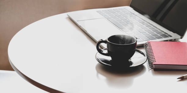 istock Workplace with open laptop, coffee cup and office supplies on white table 1176048761
