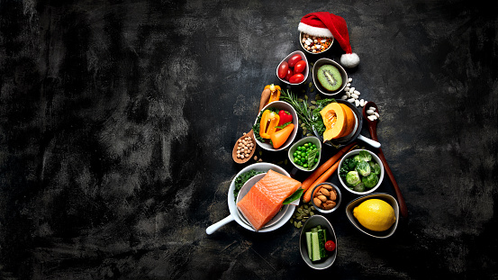 Christmas tree made of healthy food on black background. Top view with copy space.