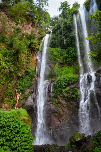 Photo of Woman stand under Sekumpul waterfall, see on falling water