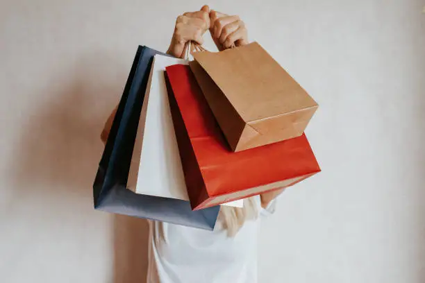 Photo of Happy woman holding in hand shopping package. Paper bag. Sale in store. Beautiful young girl in fashion shop. Customer buy present. Black friday sale. Holiday special offer, discount. Female in market