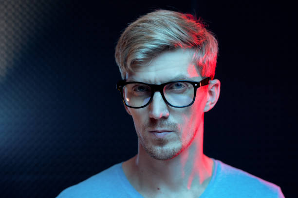 istock Young serious man with blond hair standing by wall in dark studio in isolation 1176082549