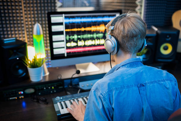 vue arrière du jeune homme dans le casque faisant la musique par l'écran d'ordinateur - audio engineer photos et images de collection