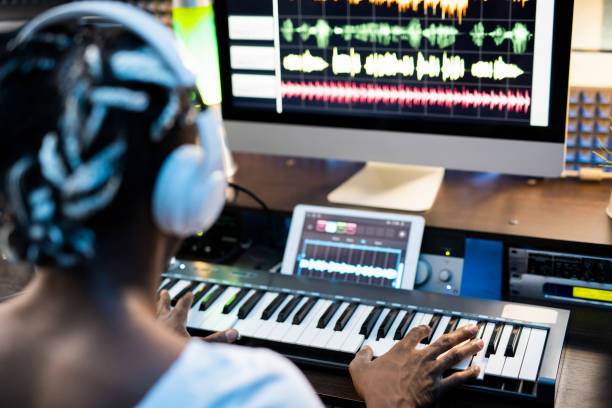 istock African or mixed-race young man touching keys of piano keyboard by computer 1176082598