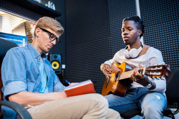 istock African man playing guitar and singing song while his colleague making notes 1176082663