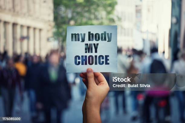 Feminist Hands Holding A Protest Banner With The Message My Body My Choice Over A Crowded Street Human Rights Concept Against Fetus Law And Reproductive Justice Stop Discrimination And Injustice Stock Photo - Download Image Now