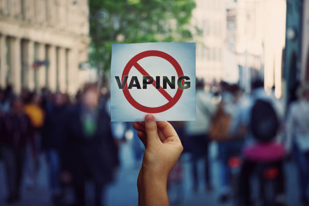 ludzka ręka trzymająca baner protestacyjny przestaje vaping wiadomości na zatłoczonym tle ulicy. zakaz aromatyzowane vaping produktów, aby zniechęcić ludzi do palenia papierosów elektronicznych. koncepcja ryzyka dla zdrowia. - harm zdjęcia i obrazy z banku zdjęć