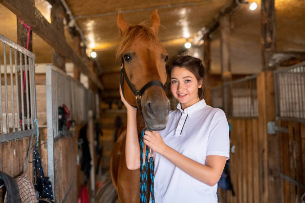 istock Pretty young smiling brunette keeping one hand by muzzle of purebred brown mare 1176087354
