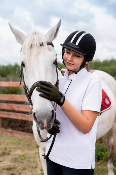 istock Young active female cuddling muzzle of white purebred racehorse 1176087433