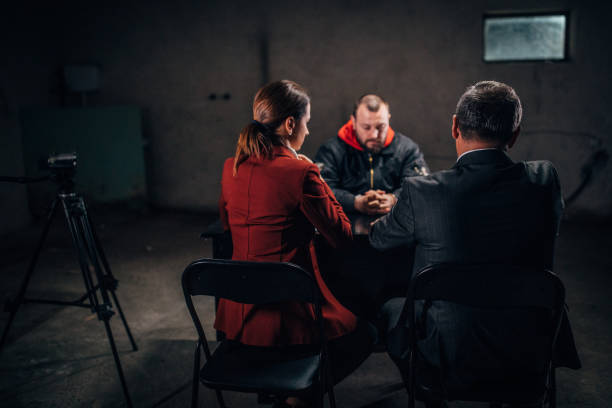 Crime Investigation Man with handcuffs and two detectives/lawyer sitting in the investigation room interrogation woman stock pictures, royalty-free photos & images