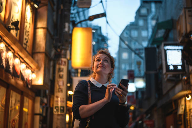 istock Caucasian Woman Using Smart Phone to Navigate Tokyo at Night 1176093251