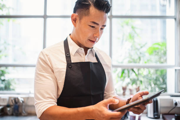 istock Chinese male barista using digital tablet at work 1176095848