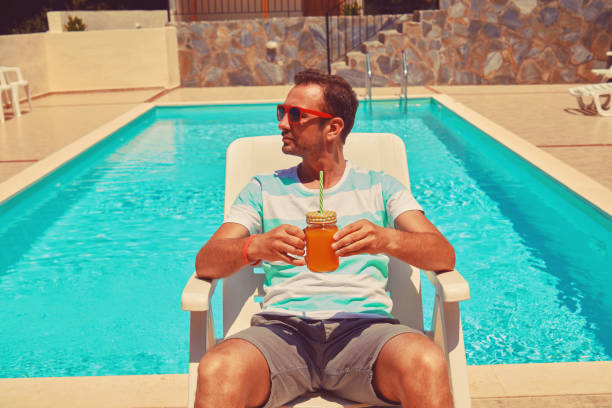 istock Attractive man drinking juice on the swimming pool. Summer concept. 1176096015