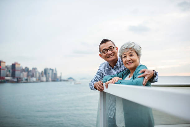 chinesische senioren, die die kamera vom ocean terminal deck aus betrachten - land in sicht stock-fotos und bilder
