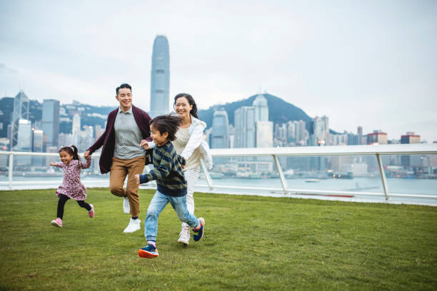 i bambini cinesi che guidano i genitori attraverso il ponte di vista - family fun running couple foto e immagini stock