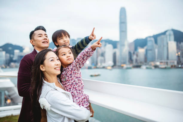 young chinese family pointing to hong views from deck - harbour city imagens e fotografias de stock