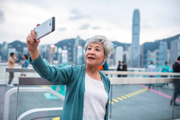 senior chinese woman taking selfie on ocean terminal deck - landwärts blicken stock-fotos und bilder