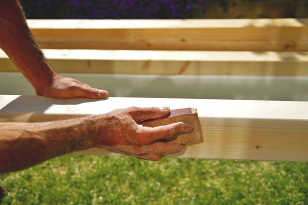 istock man's hands and arms smoothing natural wooden beam using sandpaper while he is working outside. Sanding of wood beams spruce for carport 1176100860