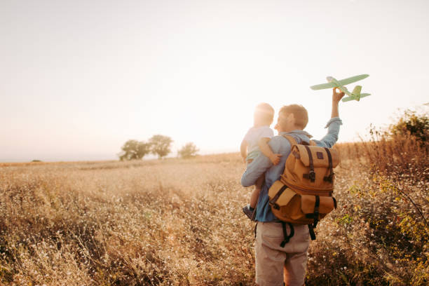 Future airplane pilot Photo of a little boy and his dad on a field. Dad is holding a model of plane and shows how it flies. piloting photos stock pictures, royalty-free photos & images