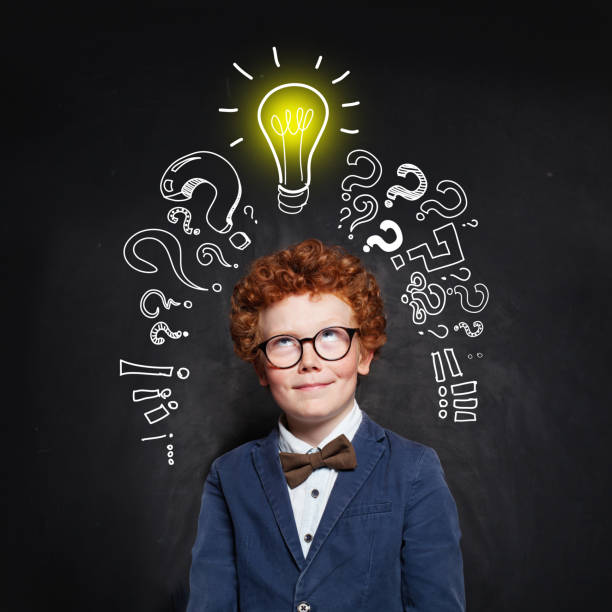 istock Little boy with ginger hair and lightbulb on chalkboard background 1176102835