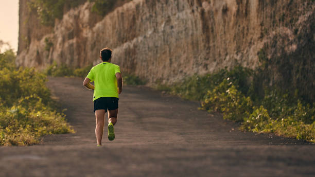 istock Man jogging on a downhill / uphill in suburb mountain road. 1176104245