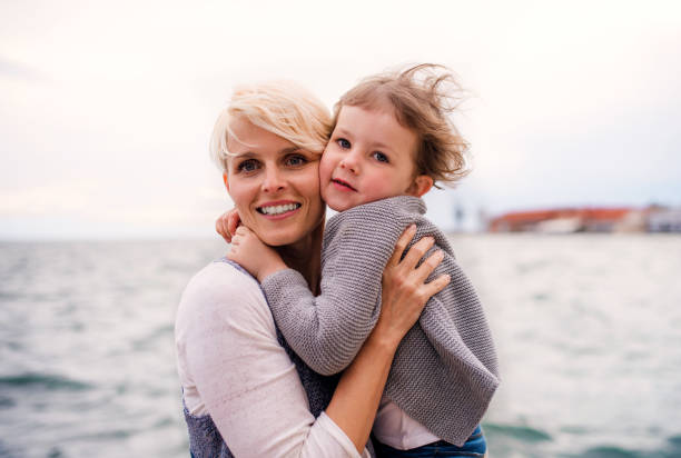 istock Young mother with small daughter standing outdoors on beach. 1176105462