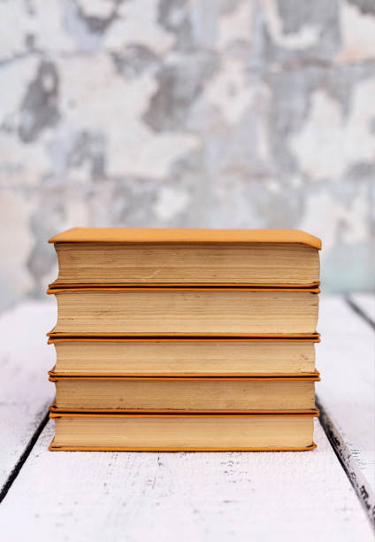 istock Stack of old ancient shabby books on a white wooden background. 1176109056