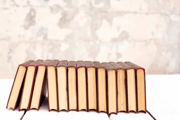 Stack of old ancient shabby books on a white wooden background. Selective focus.