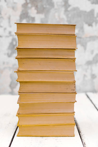 istock Stack of old ancient shabby books on a white wooden background. 1176113673
