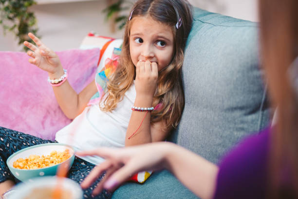 istock Little Girl Eating Popcorn While Sitting At Home 1176124203
