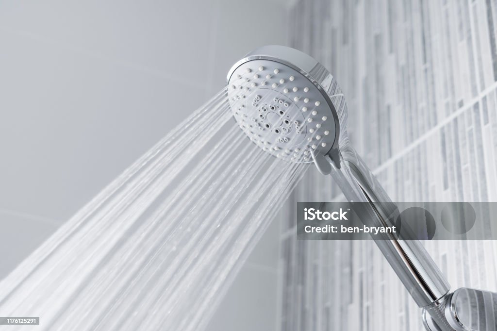 Water running from shower head and faucet in modern bathroom. Fresh shower behind wet glass window with water drops splashing. Water running from shower head and faucet in modern bathroom. Shower Head Stock Photo