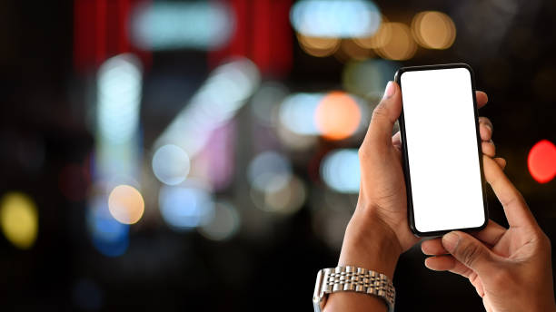 istock Man's hands holding empty screen of smartphone with night city bokeh. 1176125356