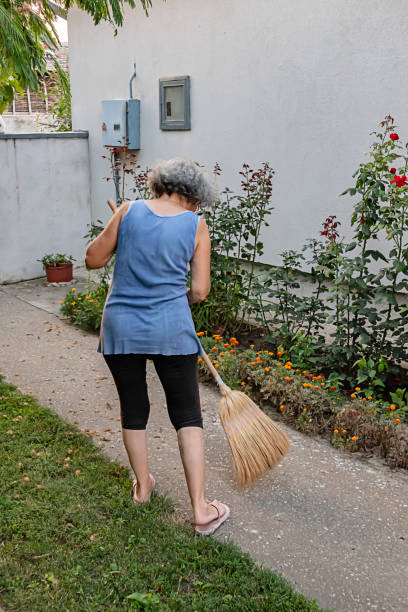 istock Senior Woman is Sweeping the Backyard with Broom 1176126538