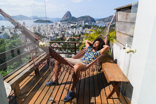 Man asleep with hands behind head, Sugarloaf Mountain in background, relaxation, on vacation, getting away from it all