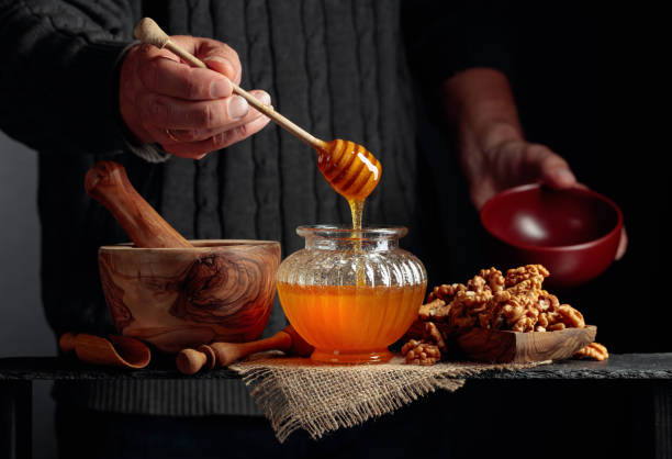 el hombre de un suéter prepara un desayuno de nueces y miel. - mortar and pestle wood healthcare and medicine jar fotografías e imágenes de stock