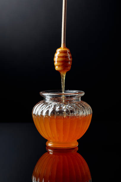 istock Honey in jar on a black reflective background. 1176127011