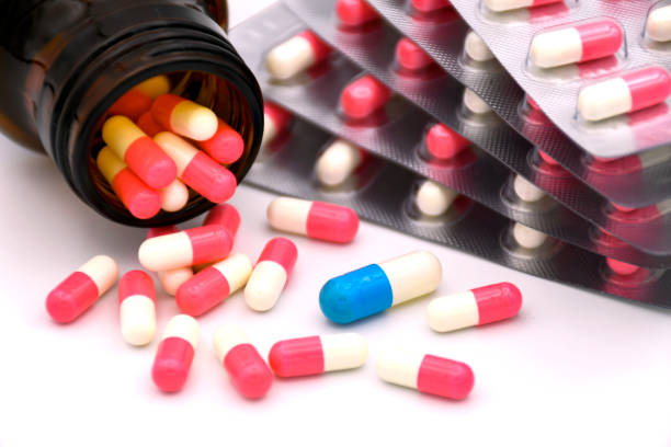 cápsula azul y blanca en un grupo de cápsulas rosas y blancas en el concepto de error de medicación. - near miss” fotografías e imágenes de stock