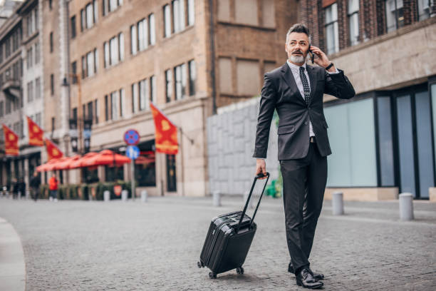 istock Handsome gentleman with luggage talking on phone 1176135331