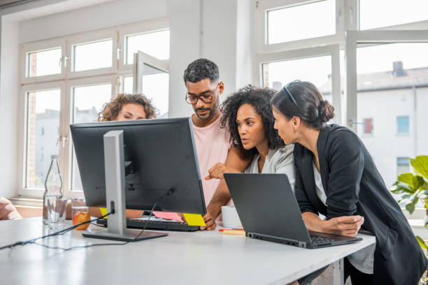 istock Small group of multi ethnic business people using a computer in the office and talking about new business ideas 1176144238